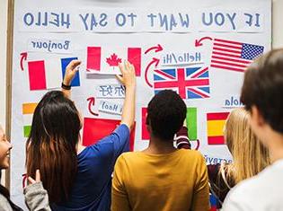 "If You Want to Say Hello" written on a white board with several country flags and language translations.